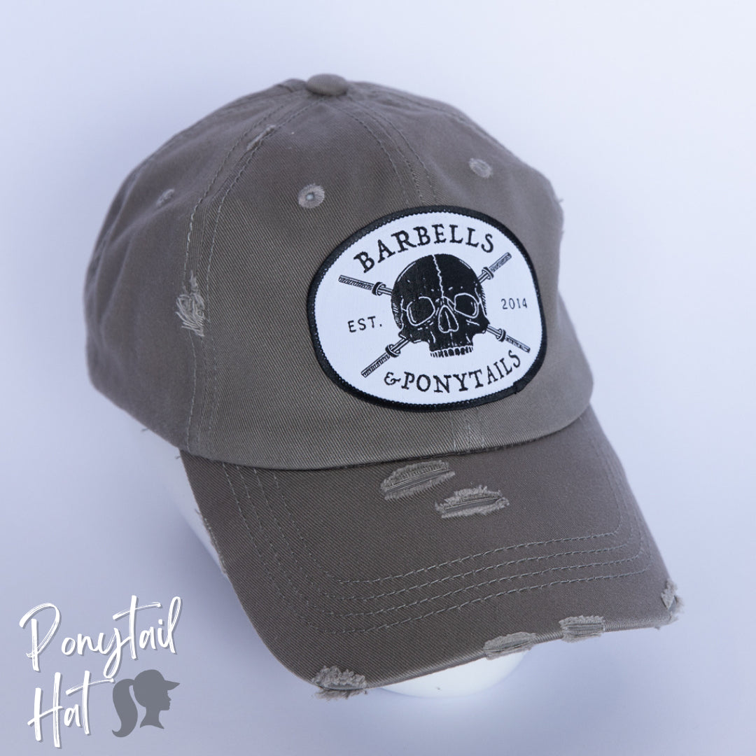 solid light grey ponytail hat with skulls and barbells text