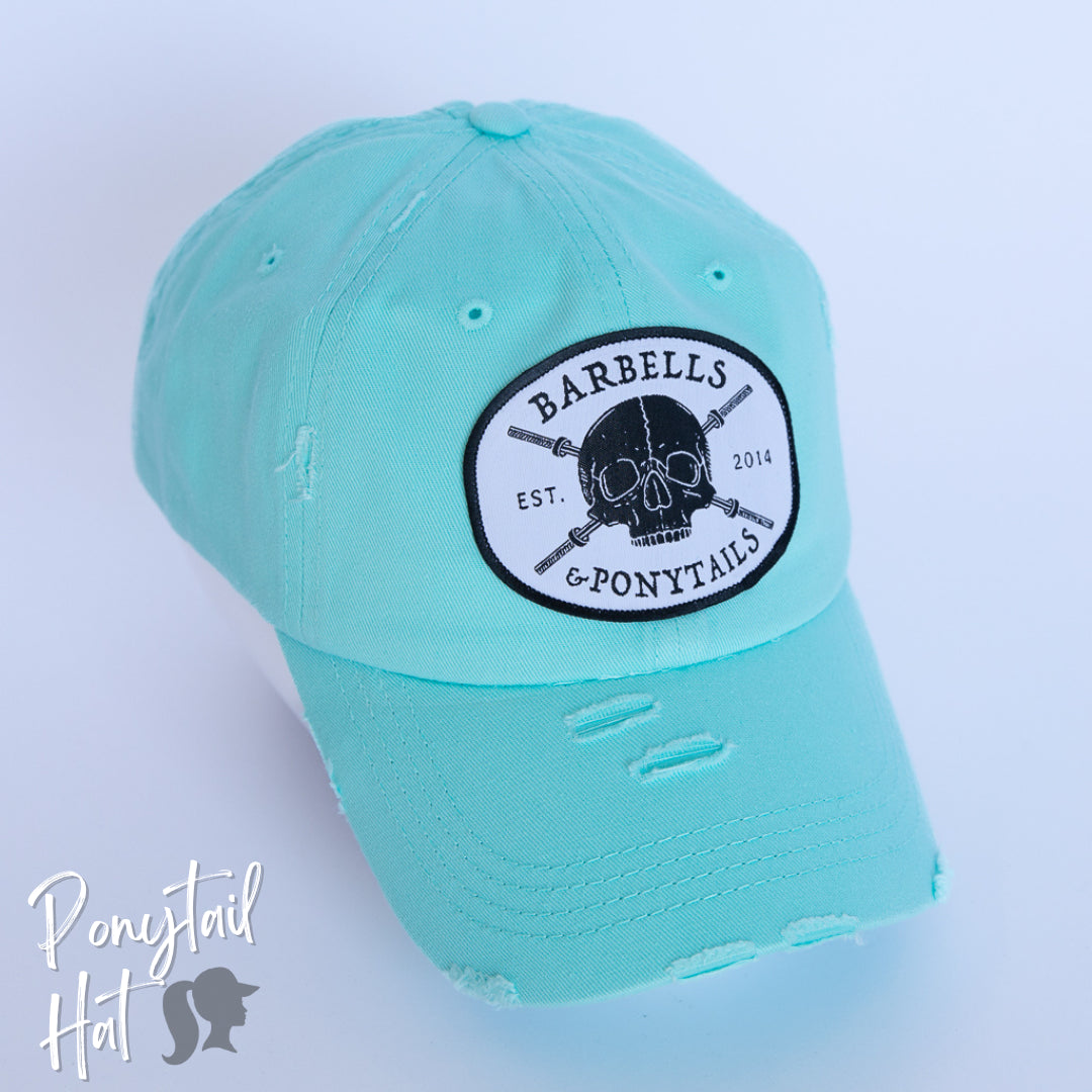 solid light blue ponytail hat with skulls and barbells text