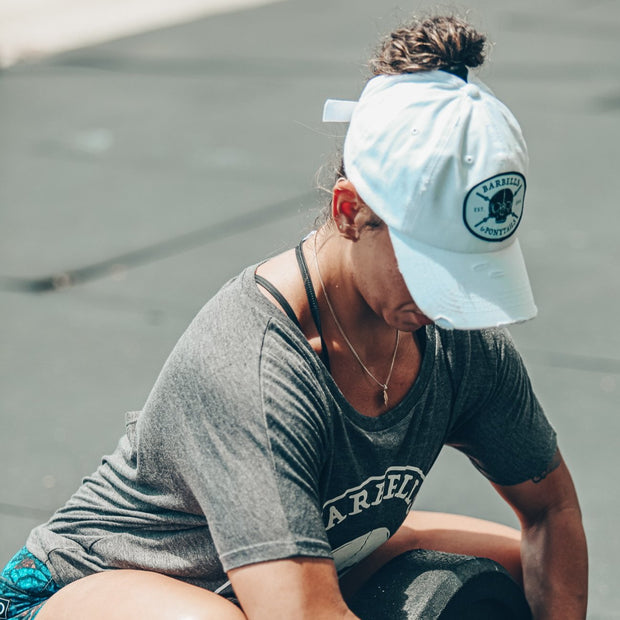 solid white ponytail hat with skulls and barbells text