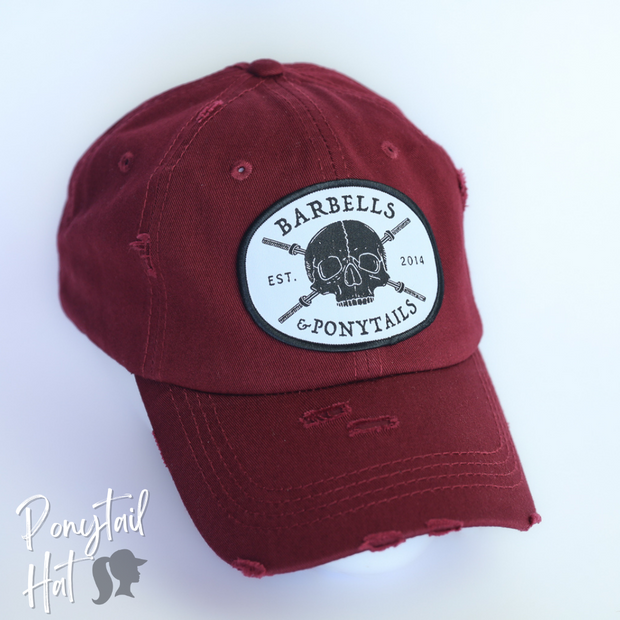 solid maroon ponytail hat with skulls and barbells text