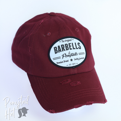 solid maroon ponytail hat with barbells and ponytails text