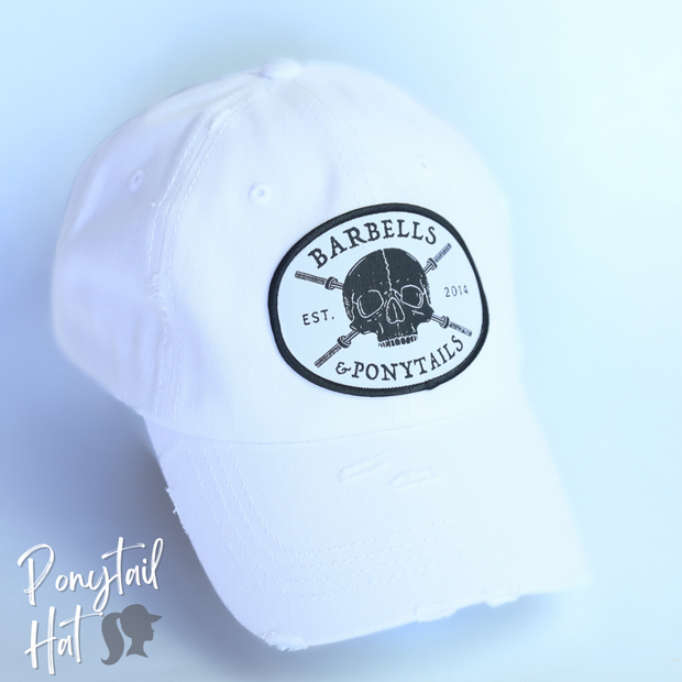 solid white ponytail hat with skulls and barbells text