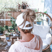 solid white ponytail hat with barbells and ponytails text